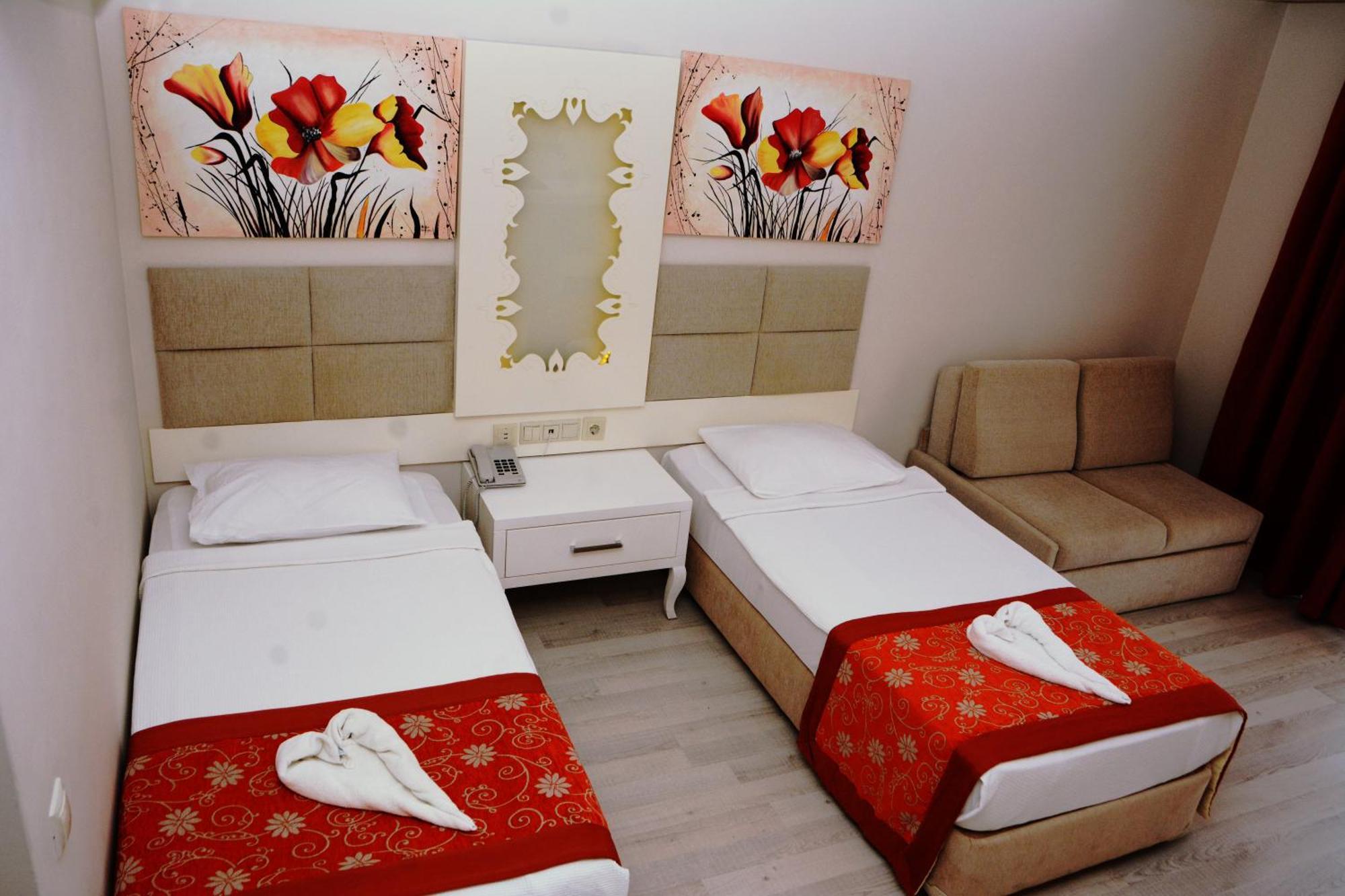 Miramor Hotel & Spa Antália Exterior foto The photo shows a hotel room featuring two single beds with white linens, each adorned with a decorative red throw. The headboards are upholstered in a light beige fabric. Above the beds, there are two large artwork pieces depicting colorful flowers.