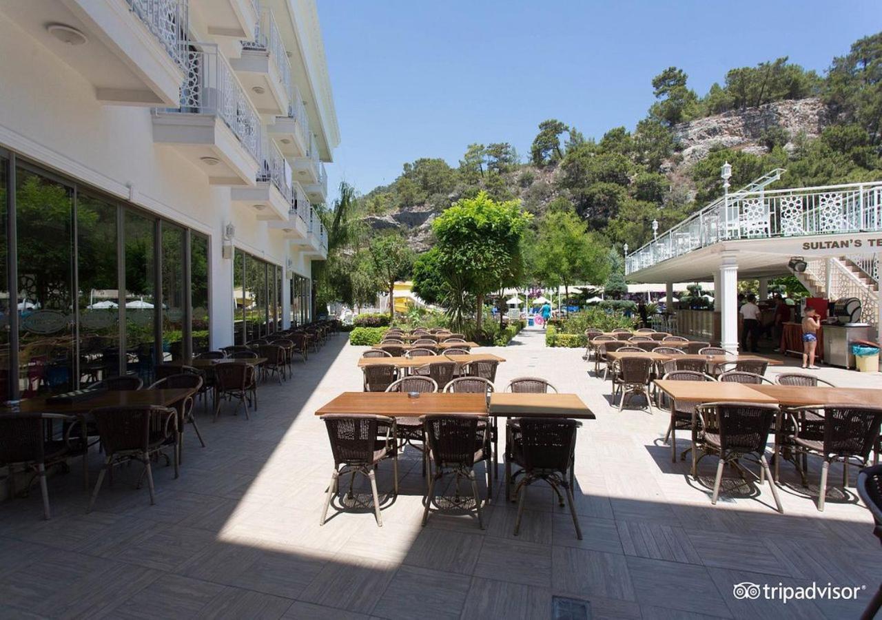 Miramor Hotel & Spa Antália Exterior foto The photo shows an outdoor dining area, likely at a restaurant or cafe. There are several tables with chairs arranged neatly on the paved ground, and some greenery, such as trees and plants, is visible in the background. The setting appears bright an